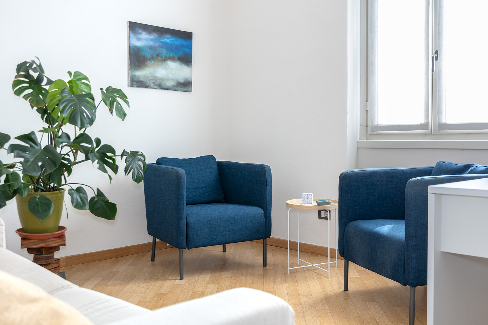 Lo studio: due poltrone blu, una pianta e una finestra luminosa